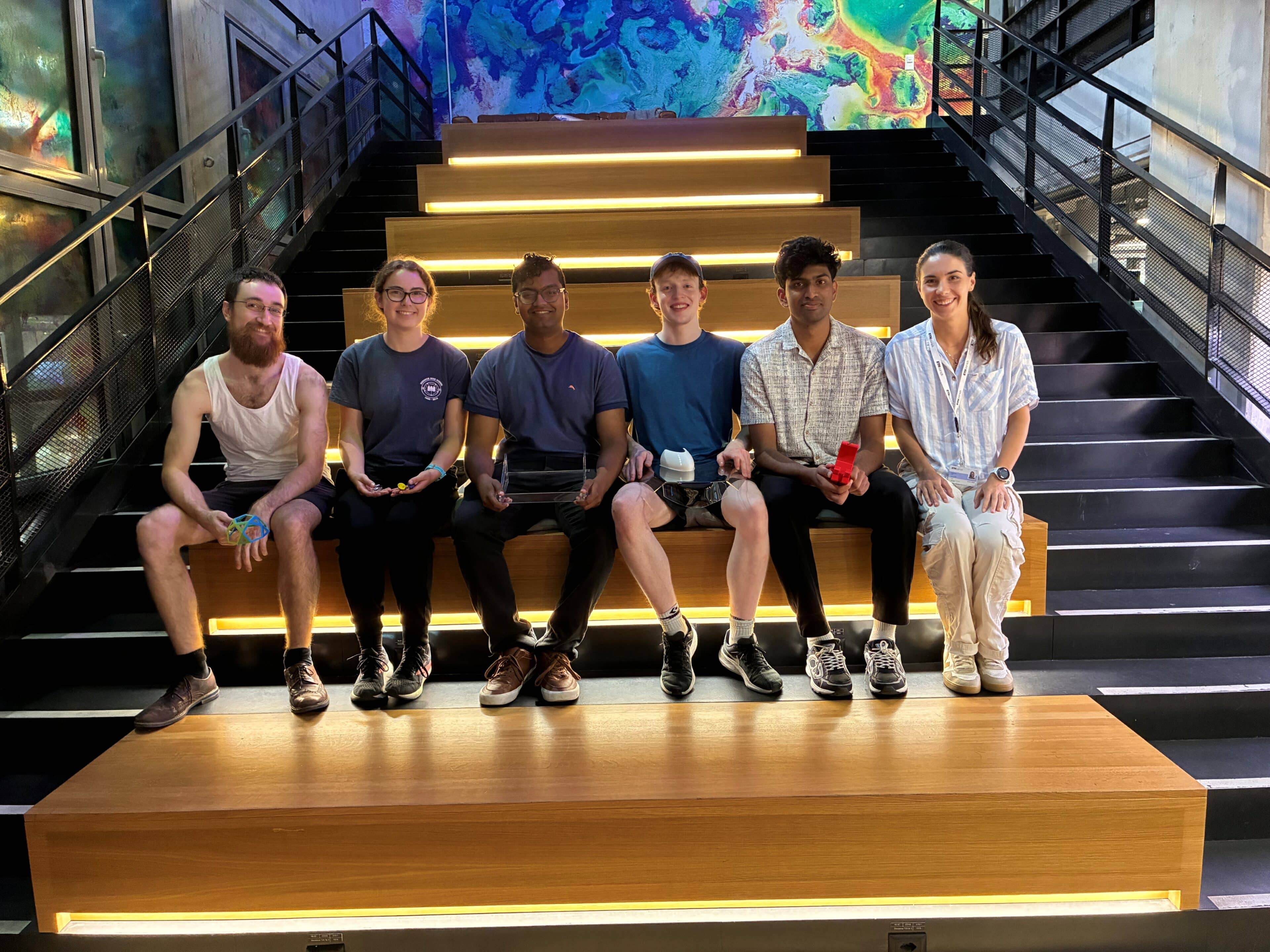 Young people sitting on a staircase holding projects they created